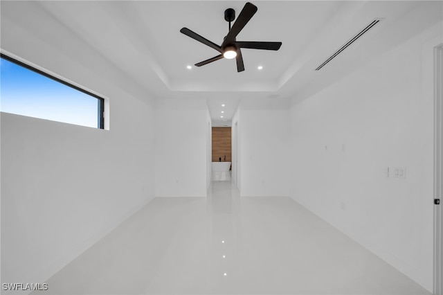 unfurnished room featuring a raised ceiling and ceiling fan