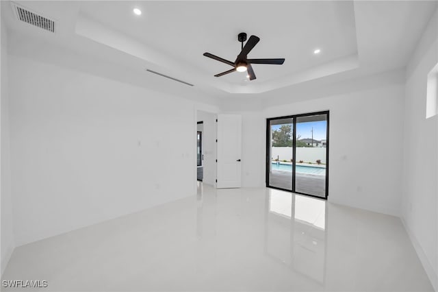 unfurnished room with a raised ceiling, light tile patterned flooring, and ceiling fan