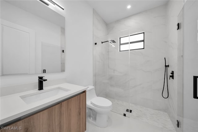 bathroom with vanity, a shower with door, and toilet