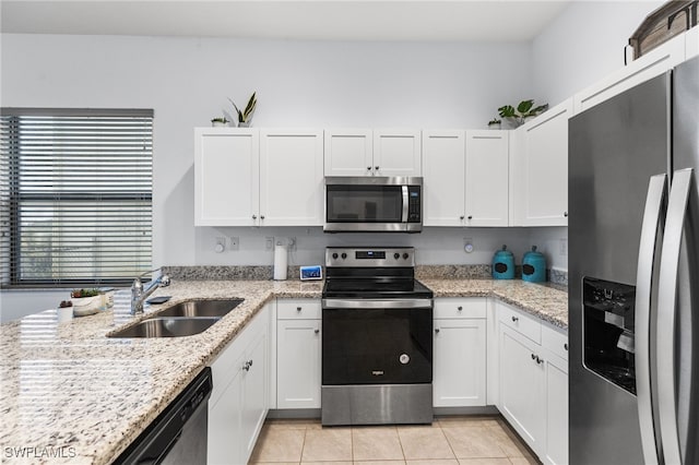 kitchen featuring appliances with stainless steel finishes, white cabinetry, sink, light tile patterned floors, and light stone counters