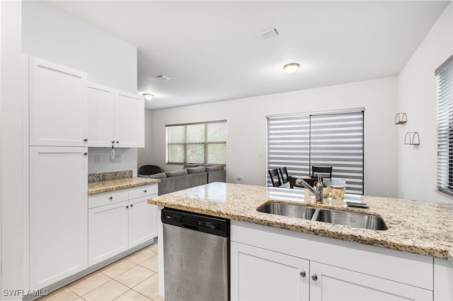 kitchen featuring a wealth of natural light, white cabinetry, sink, stainless steel dishwasher, and light stone counters