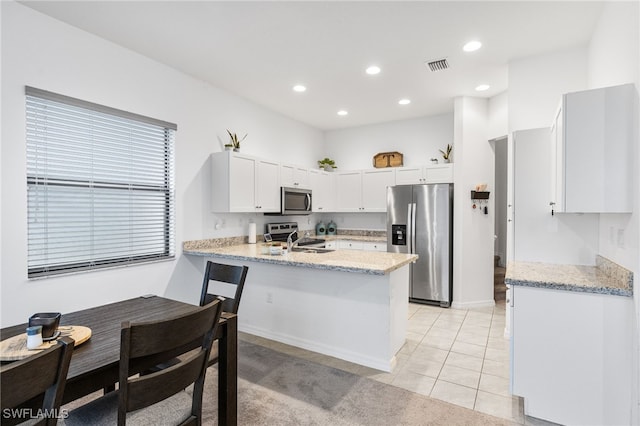 kitchen featuring white cabinetry, light tile patterned floors, kitchen peninsula, stainless steel appliances, and light stone countertops