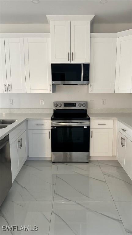 kitchen with appliances with stainless steel finishes, sink, and white cabinets