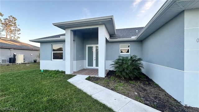 property entrance featuring cooling unit, a yard, and french doors