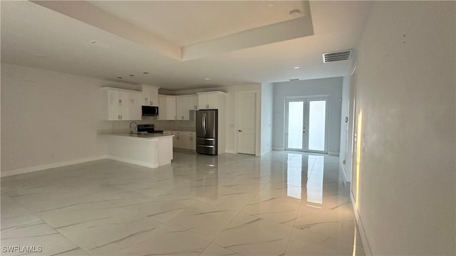 kitchen featuring appliances with stainless steel finishes, white cabinets, kitchen peninsula, a raised ceiling, and french doors