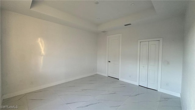 unfurnished bedroom with a closet and a raised ceiling