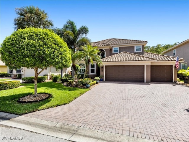 mediterranean / spanish house featuring a garage and a front yard