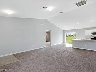 unfurnished living room featuring vaulted ceiling and carpet flooring