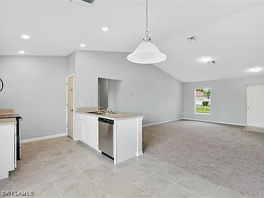 kitchen with pendant lighting, sink, white cabinetry, and stainless steel dishwasher