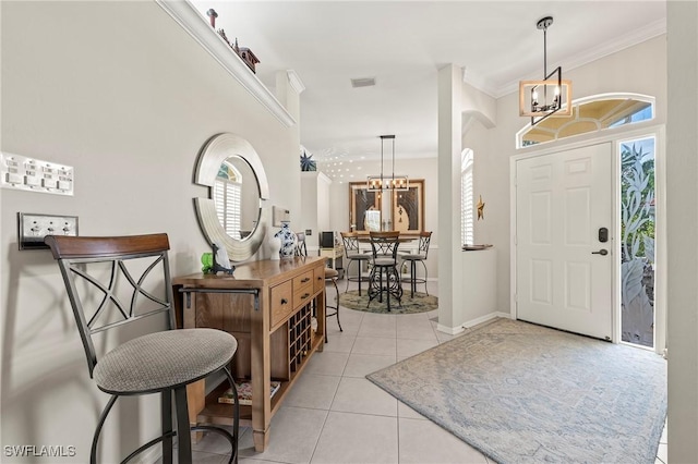 tiled foyer entrance with crown molding and a notable chandelier