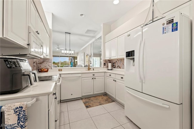 kitchen featuring sink, white appliances, light tile patterned floors, white cabinets, and decorative light fixtures