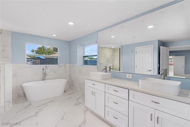 bathroom with vanity, a bathing tub, and tile walls