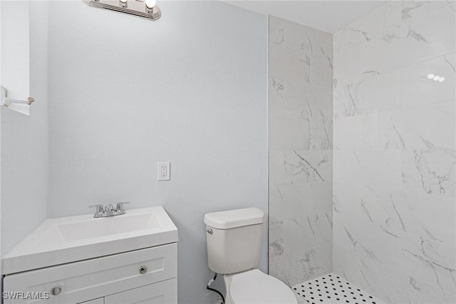 bathroom with vanity, toilet, and a tile shower