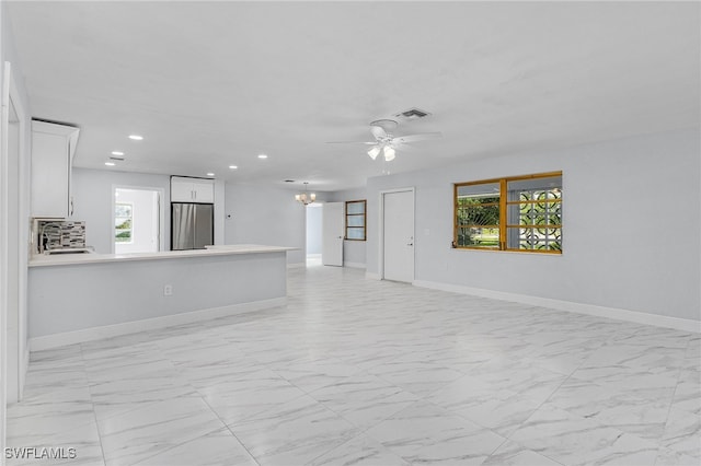 unfurnished living room with ceiling fan with notable chandelier