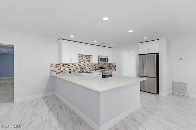 kitchen with appliances with stainless steel finishes, tasteful backsplash, white cabinetry, sink, and kitchen peninsula