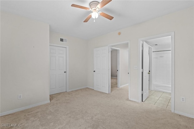 unfurnished bedroom featuring light colored carpet, ceiling fan, and ensuite bathroom