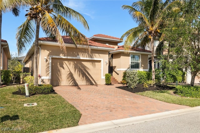 mediterranean / spanish-style house with a garage, a tiled roof, decorative driveway, and stucco siding