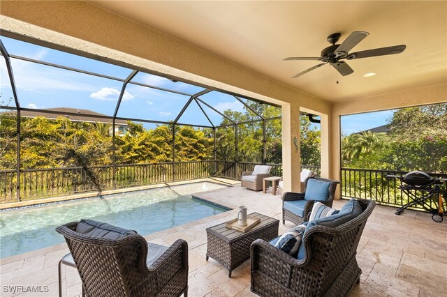 view of pool featuring ceiling fan, a patio, outdoor lounge area, and glass enclosure