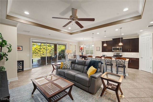 living room with baseboards, visible vents, a raised ceiling, ornamental molding, and light tile patterned flooring