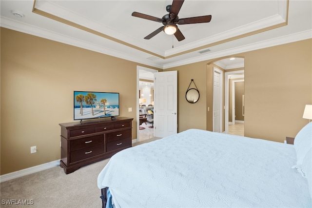 bedroom featuring light carpet, visible vents, arched walkways, a raised ceiling, and baseboards