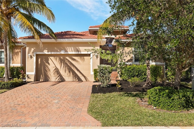 view of front facade with a garage, a tiled roof, decorative driveway, and stucco siding