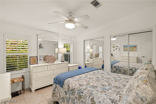 bedroom with lofted ceiling, ceiling fan, multiple closets, and light tile patterned flooring