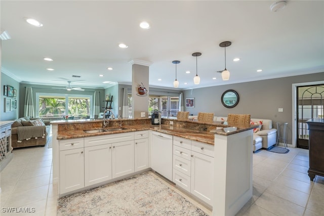 kitchen featuring sink, dark stone countertops, white cabinets, and pendant lighting