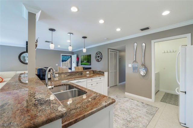 kitchen featuring white fridge, dark stone countertops, sink, white cabinetry, and decorative light fixtures