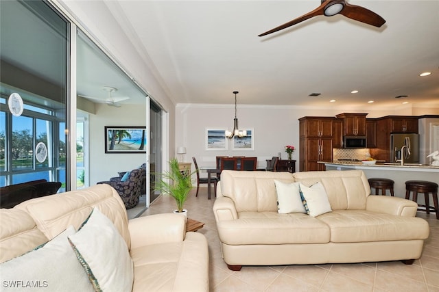 living room featuring light tile patterned floors, ceiling fan with notable chandelier, and ornamental molding