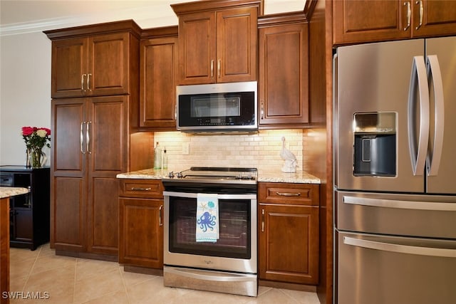 kitchen featuring light tile patterned flooring, light stone counters, ornamental molding, appliances with stainless steel finishes, and decorative backsplash