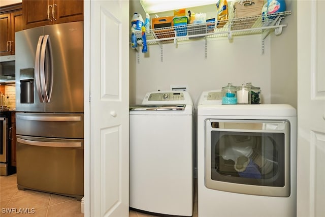 clothes washing area featuring light tile patterned floors and washing machine and dryer