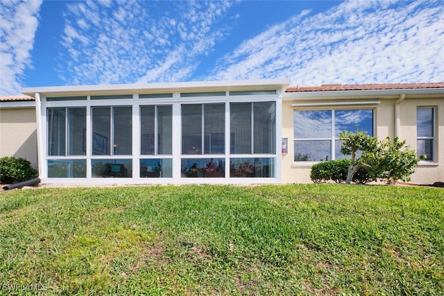 back of house featuring a yard and a sunroom