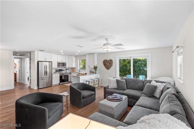 living room with ceiling fan, sink, and light hardwood / wood-style floors