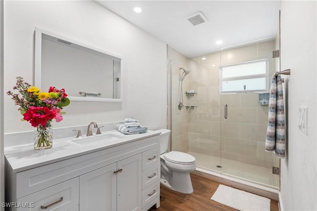 bathroom with hardwood / wood-style flooring, walk in shower, vanity, and toilet