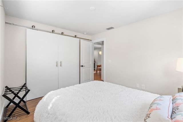 bedroom featuring a closet, light hardwood / wood-style flooring, and a barn door