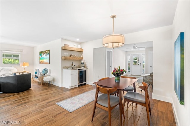 dining space featuring wine cooler, a wealth of natural light, light hardwood / wood-style floors, and bar