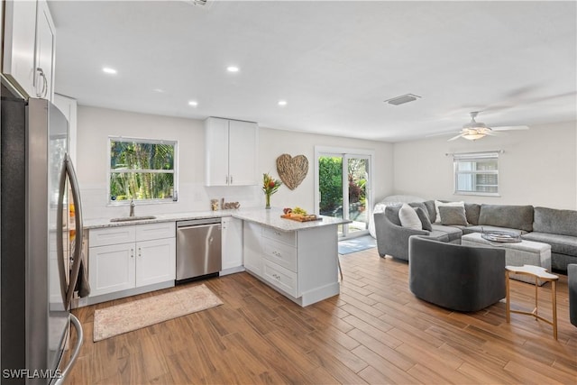 kitchen featuring sink, stainless steel appliances, kitchen peninsula, and white cabinets