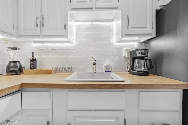 kitchen featuring tasteful backsplash, white cabinetry, and sink