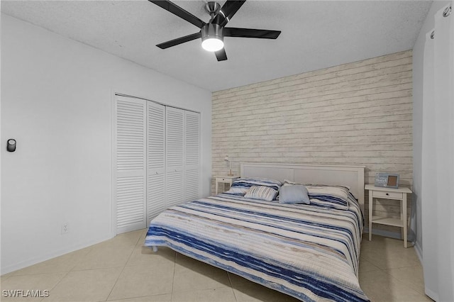 tiled bedroom with a textured ceiling, ceiling fan, and a closet