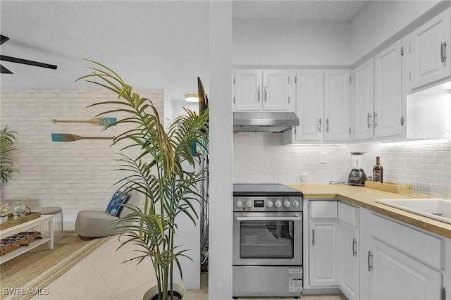 kitchen with tasteful backsplash, white cabinets, light tile patterned floors, electric range, and ceiling fan