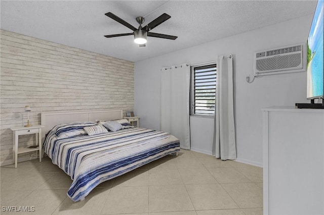 bedroom with wood walls, a textured ceiling, light tile patterned floors, a wall unit AC, and ceiling fan