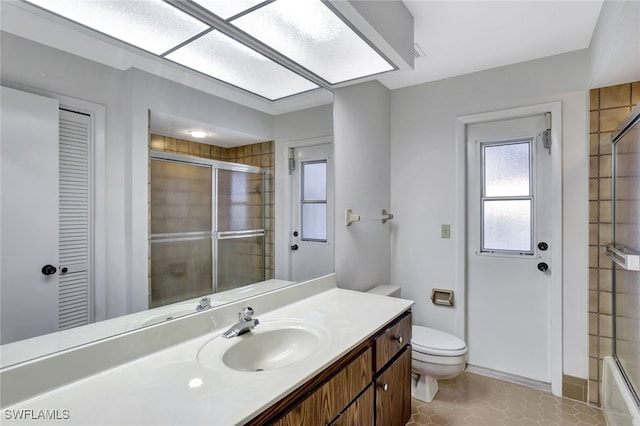 full bathroom with tile patterned flooring, vanity, enclosed tub / shower combo, and toilet