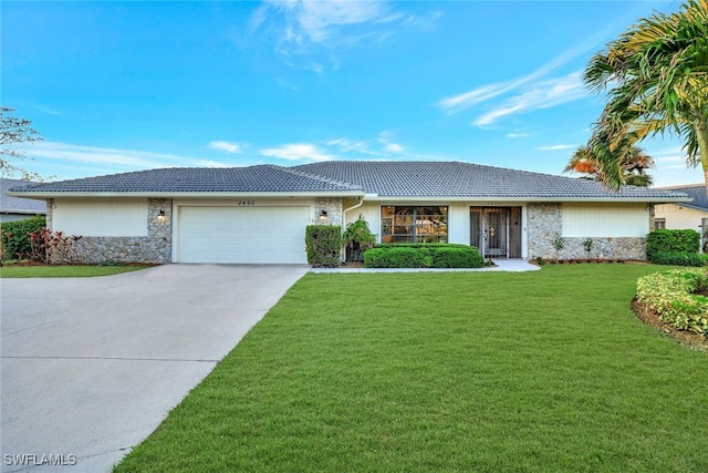 ranch-style house featuring a garage and a front lawn