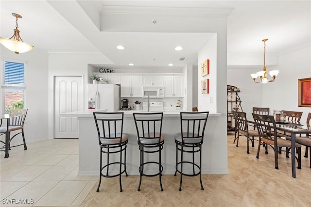 kitchen featuring white cabinetry, a breakfast bar area, hanging light fixtures, light tile patterned floors, and white appliances