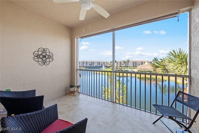 sunroom featuring ceiling fan and a water view