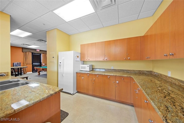 kitchen featuring sink, white appliances, a paneled ceiling, billiards, and light stone counters