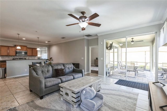 living room with ceiling fan, ornamental molding, and light tile patterned floors