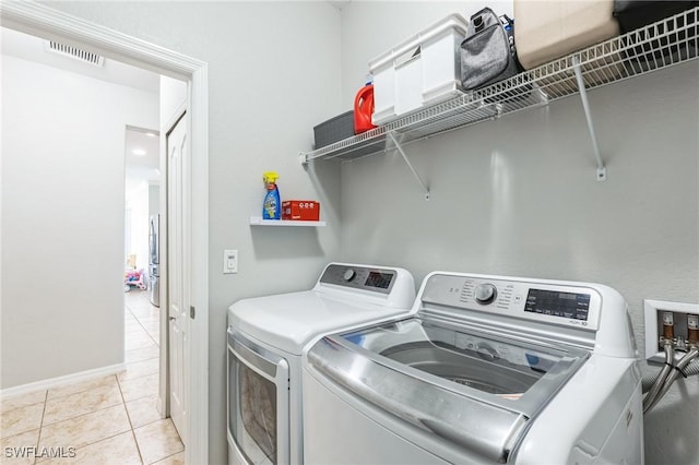 laundry area featuring washing machine and clothes dryer and light tile patterned floors