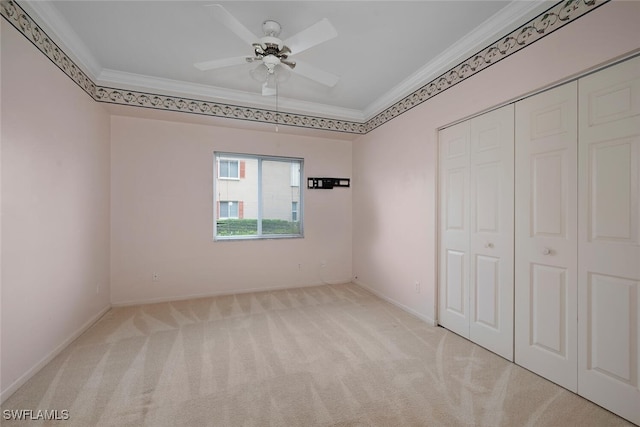 unfurnished bedroom featuring light carpet, ornamental molding, a closet, and ceiling fan