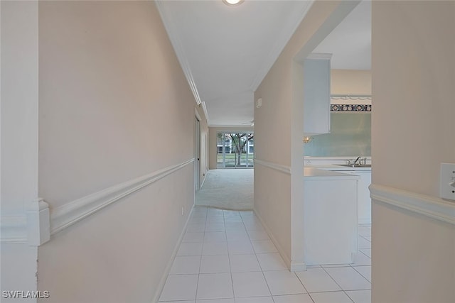 corridor featuring crown molding, sink, and light tile patterned floors